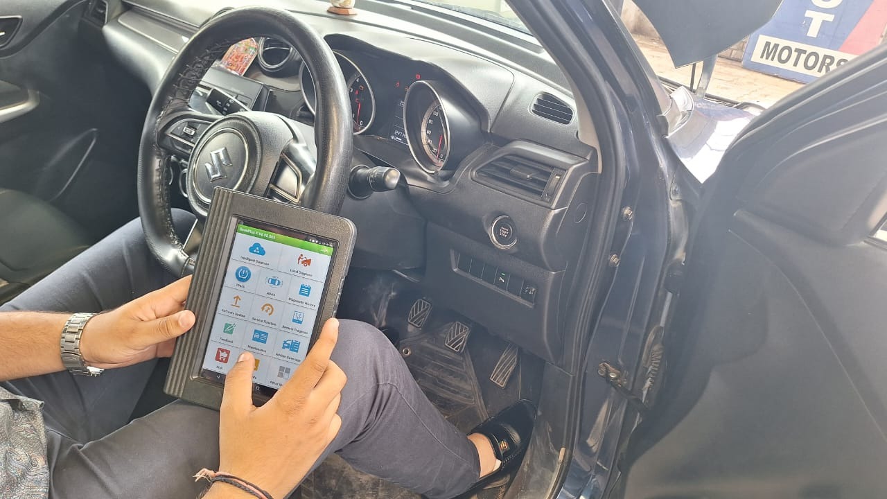 Technician using digital diagnostic tablet on Maruti Suzuki vehicle